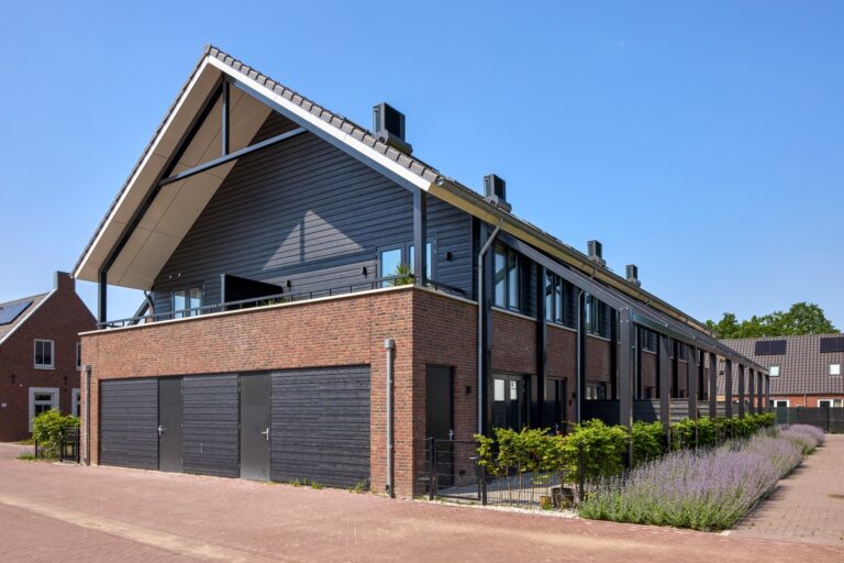 Voorgevel van een moderne hoekwoning met zwarte houten gevel en bakstenen plint