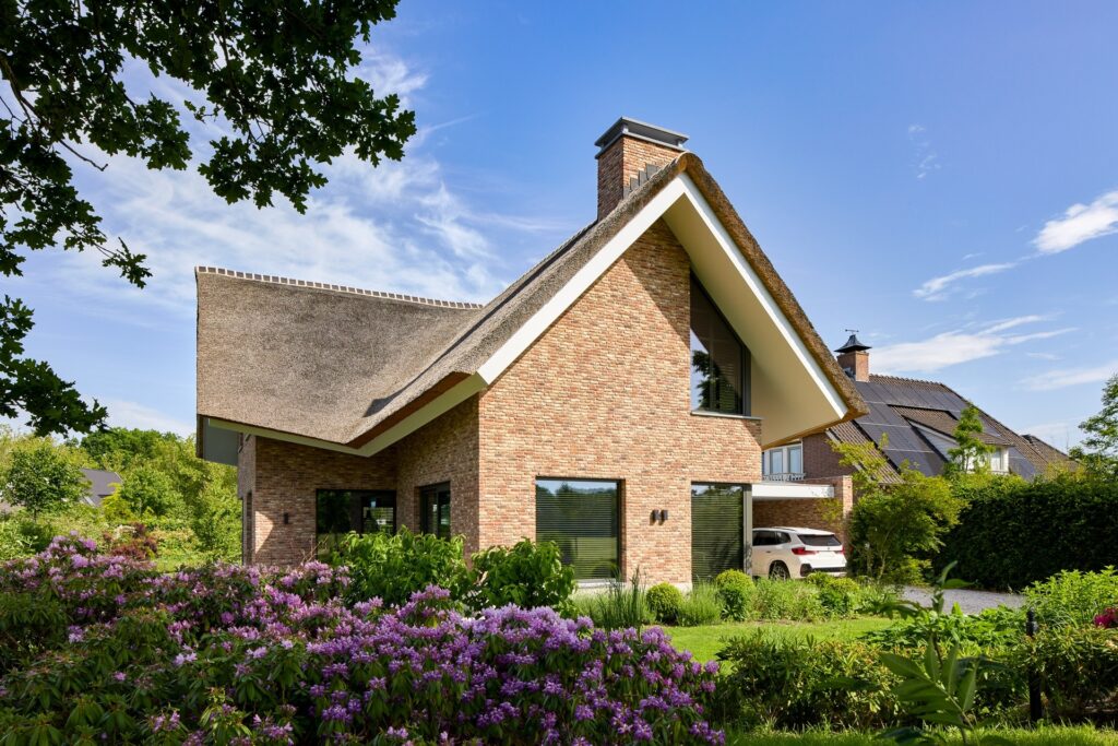 Landelijke woning met rieten dak omringd door een groene tuin