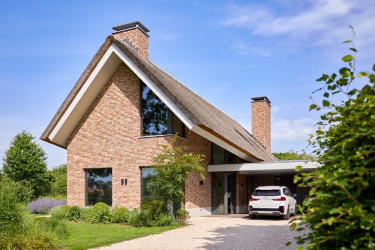 Landelijke bakstenen woning met rieten kap, grindoprit en geïntegreerde carport