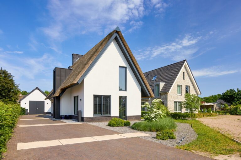 Vrijstaande rietgedekte woning met moderne vormgeving en strak aangelegde voortuin.