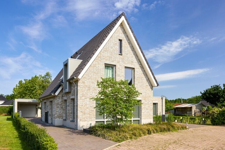 Moderne vrijstaande woning met lichte bakstenen gevel, zonnepanelen en eigentijdse architectuur.