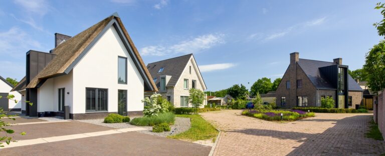 Vrijstaande nieuwbouwwoning met lichte gevelsteen, zadeldak en aangebouwde garage.