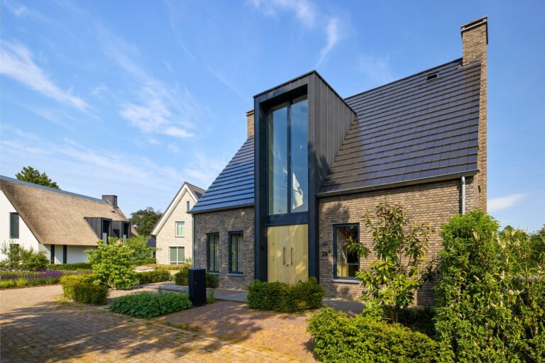 Symmetrische voorgevel van een moderne woning met hoge glazen entree en donkere baksteen
