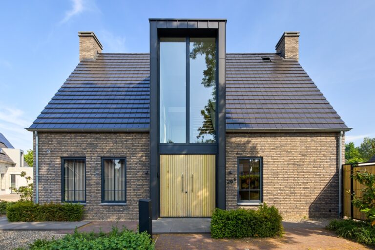 Vrijstaande woning met eigentijdse architectuur, donkere gevelsteen en opvallende glazen entree