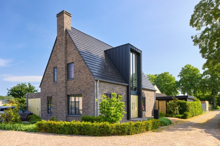Moderne villa met donkere baksteen, hoge entree en luxe architectuur in een groene woonwijk