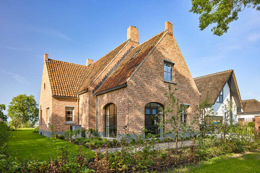 Landelijke bakstenen woning met rode pannendaken en grote boogramen in Lith