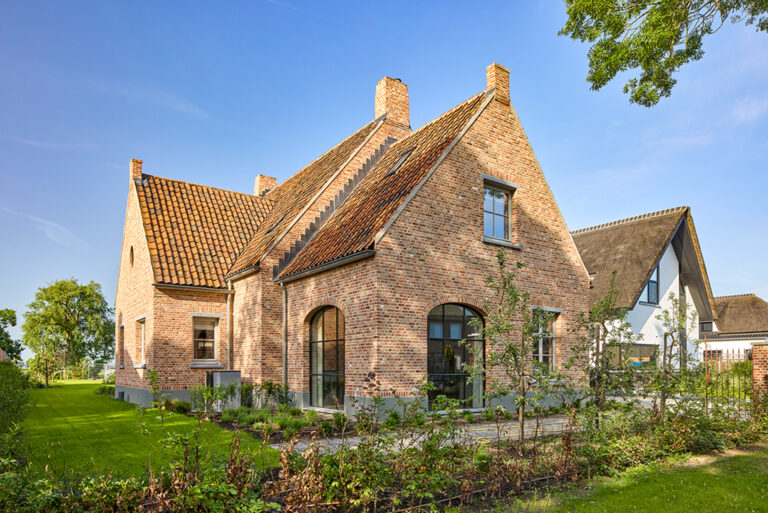 Landelijke bakstenen woning met rode pannendaken en grote boogramen in Lith