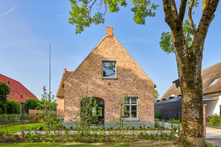 Landelijke bakstenen woning met rode pannendaken en grote boogramen in Lith