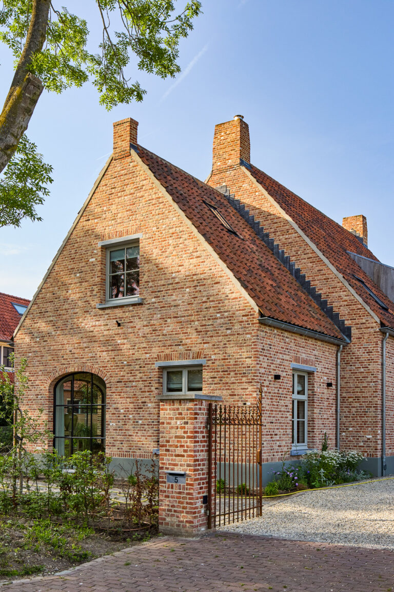 Landelijke bakstenen woning met rode pannendaken en grote boogramen in Lith