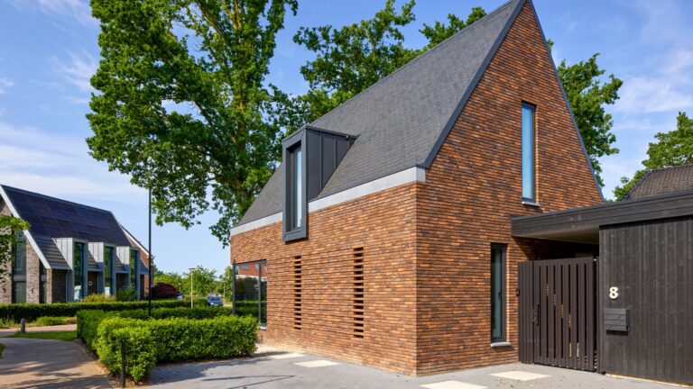 Eigentijdse woning waarin warme baksteen, een markante kap en donkere houten details samenkomen in een krachtig en sfeervol ontwerp.