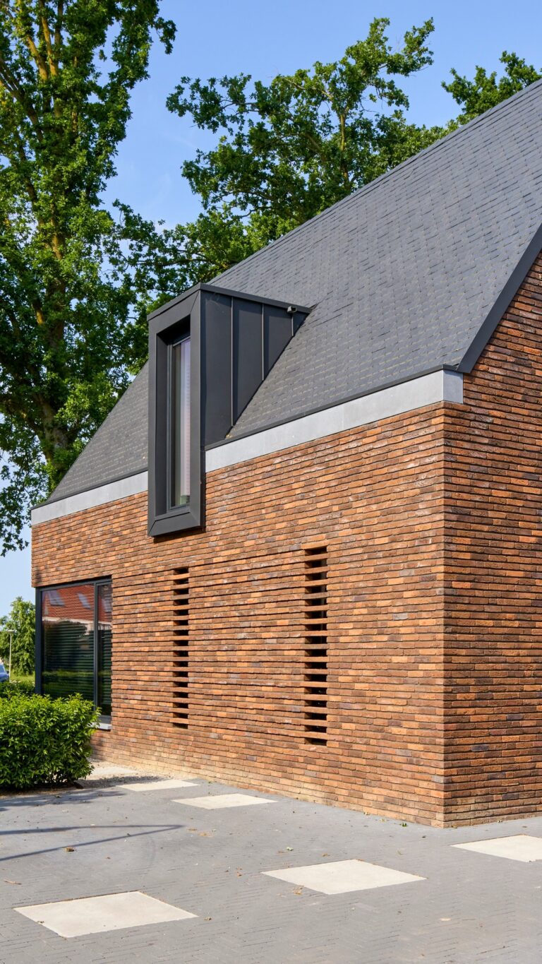 Eigentijdse woning waarin warme baksteen, een markante kap en donkere houten details samenkomen in een krachtig en sfeervol ontwerp.