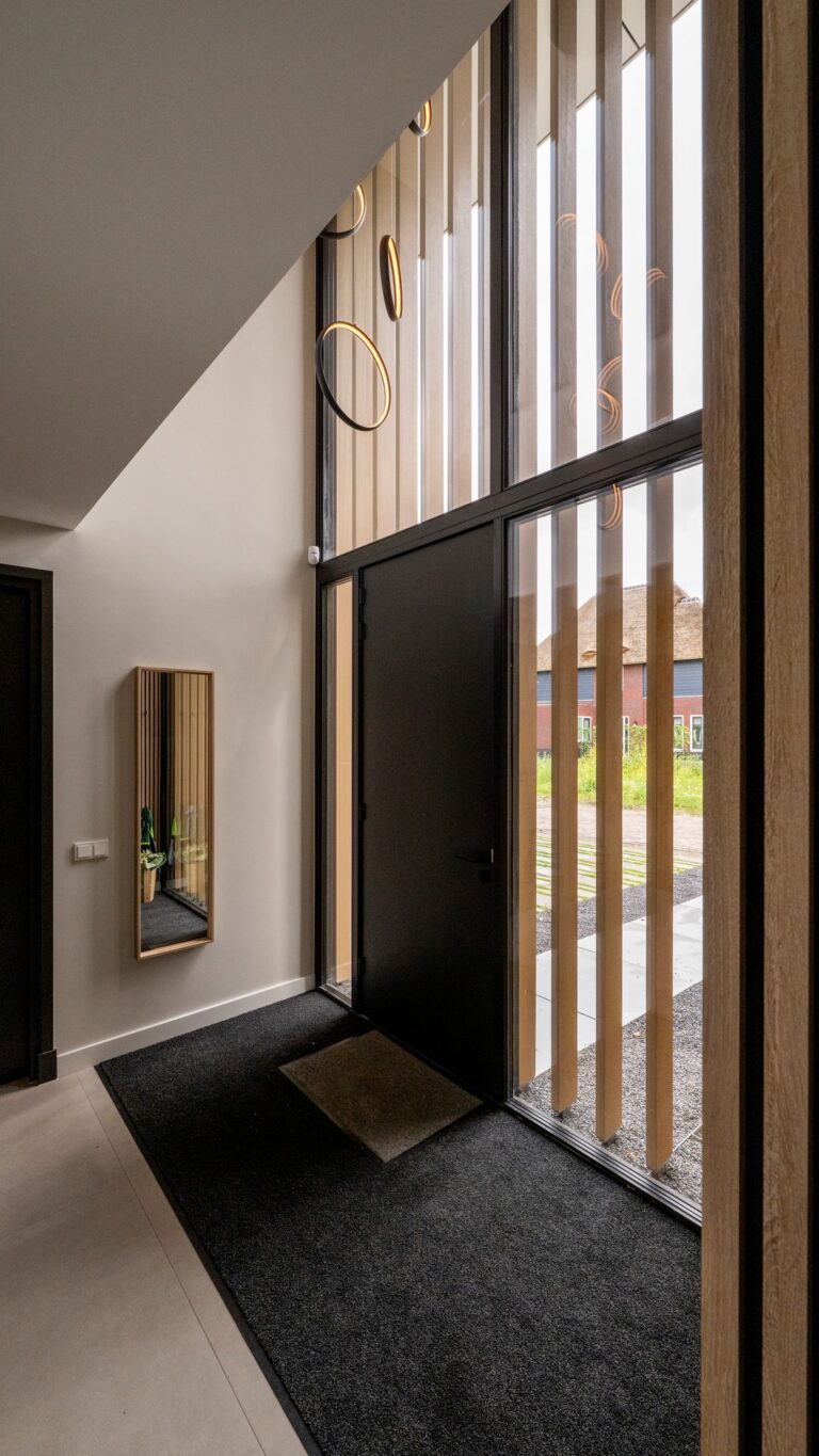Hoge entree van eigentijdse woning in Nijmegen met glas en verticale houten lamellen